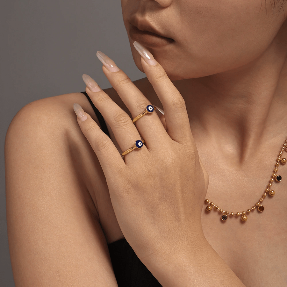 Stylish woman wearing evil eye stackable rings with watch at urban cafe
