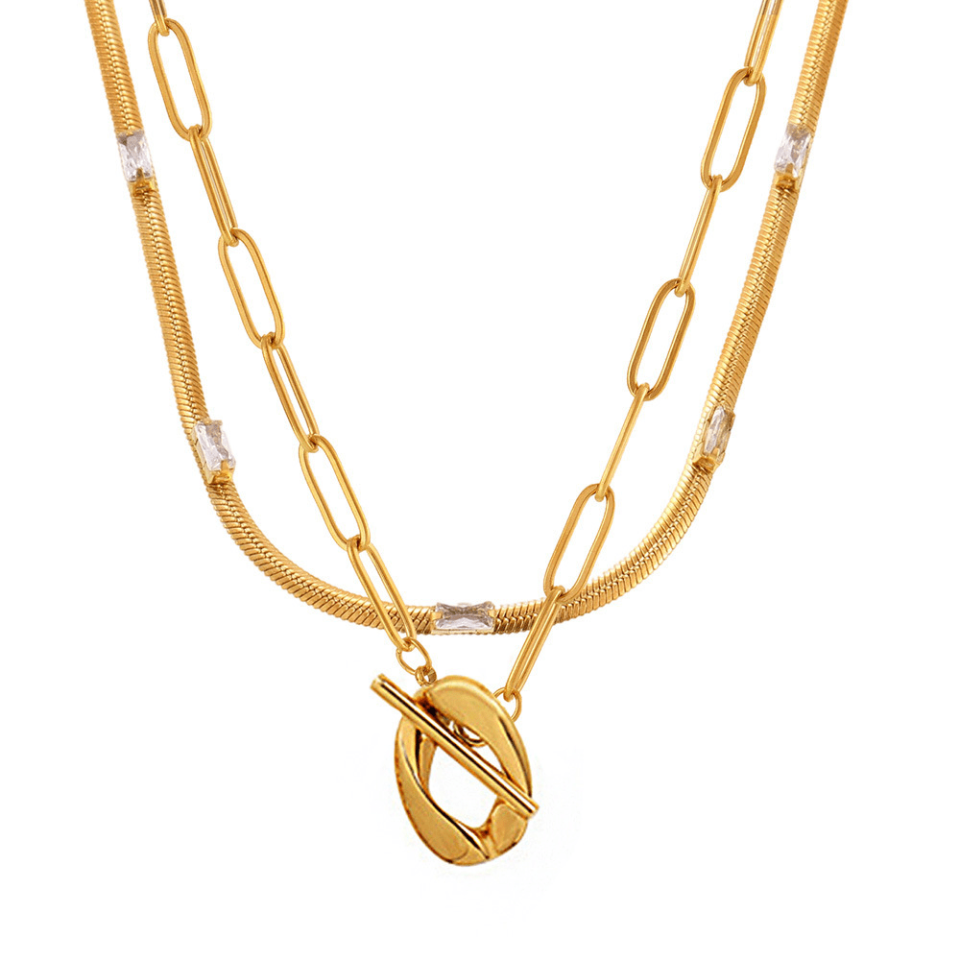 Flat lay of Oudada gold blade chain and white CZ pendant necklace on marble, luxury jewelry collection
