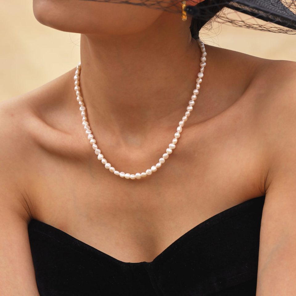 Close‑up of model’s hand adjusting P1282 freshwater pearl choker necklace clasp