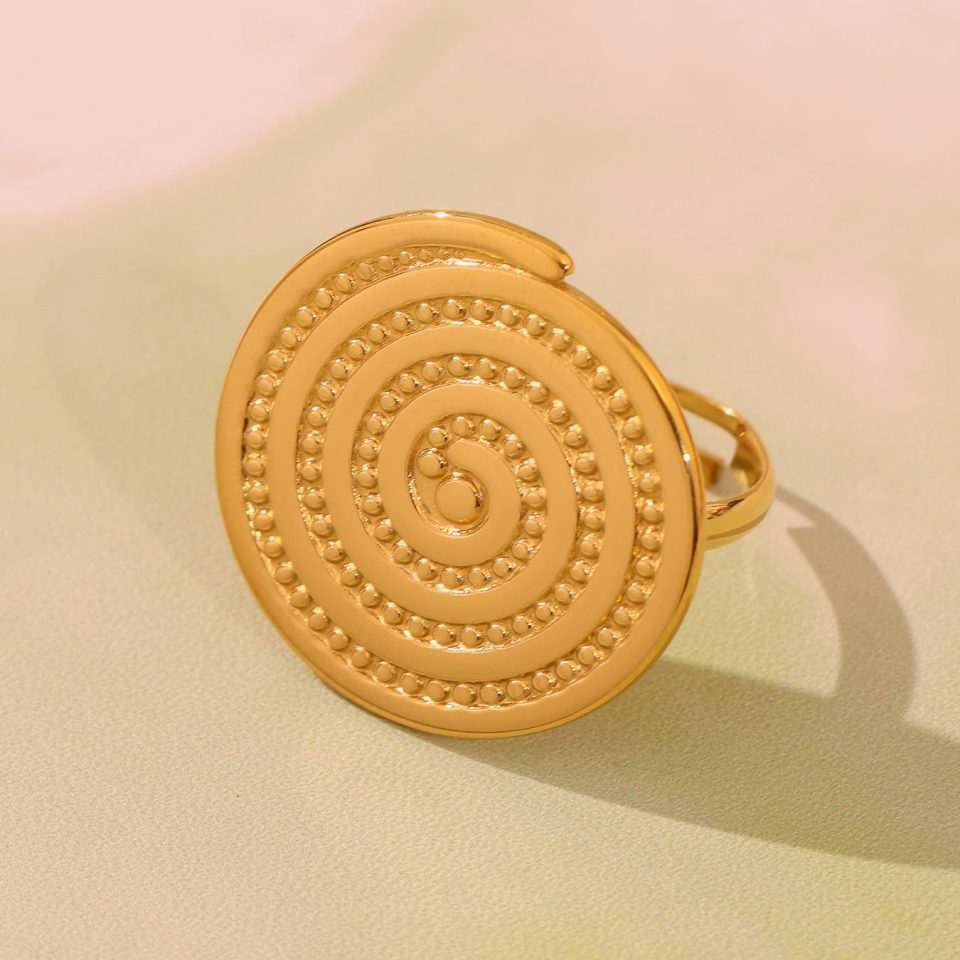 A gold circular groove open ring with a hat design, displayed in a fashionable scene.
