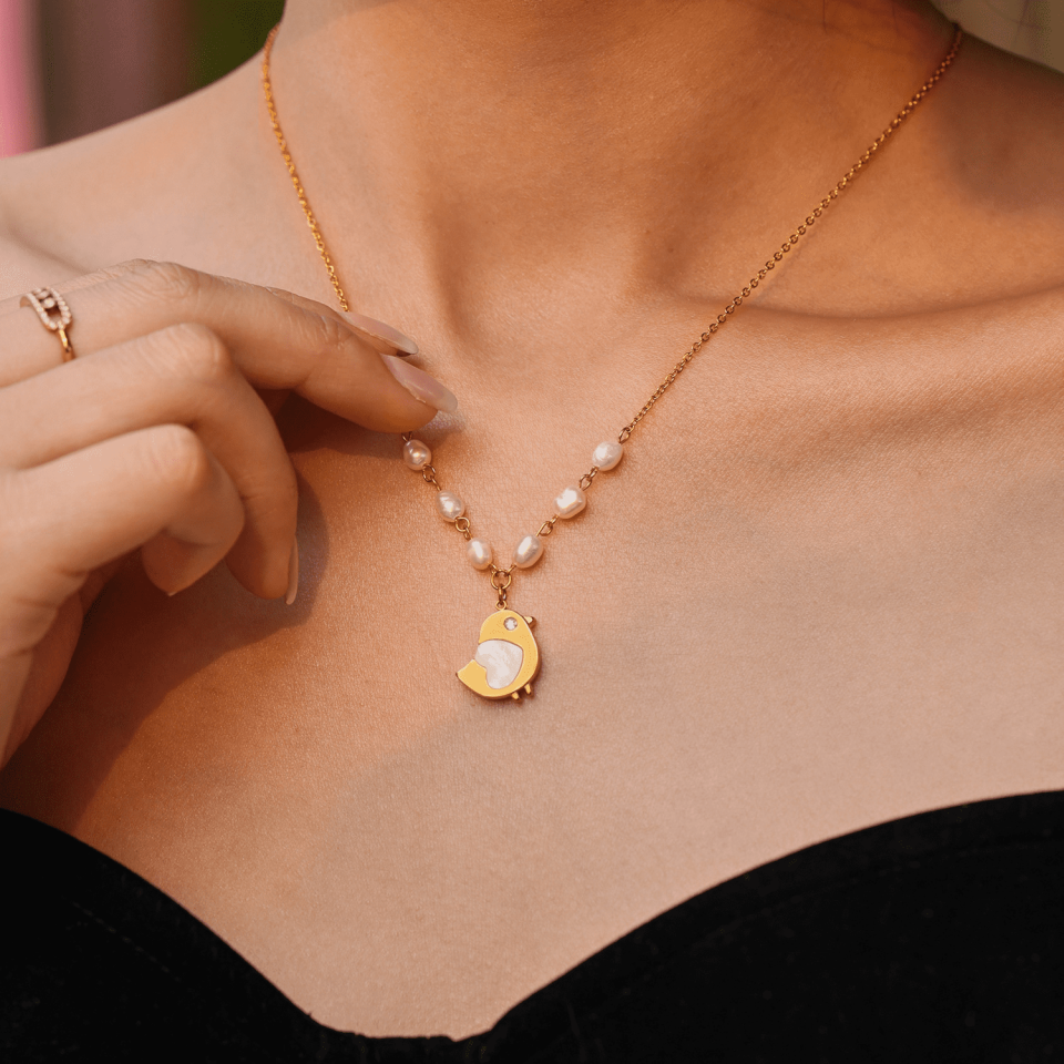 A model wearing the Chick Shell Pearl Necklace - Steel Shell Jewelry with a V-neck outfit, showcasing the perfect pairing.
