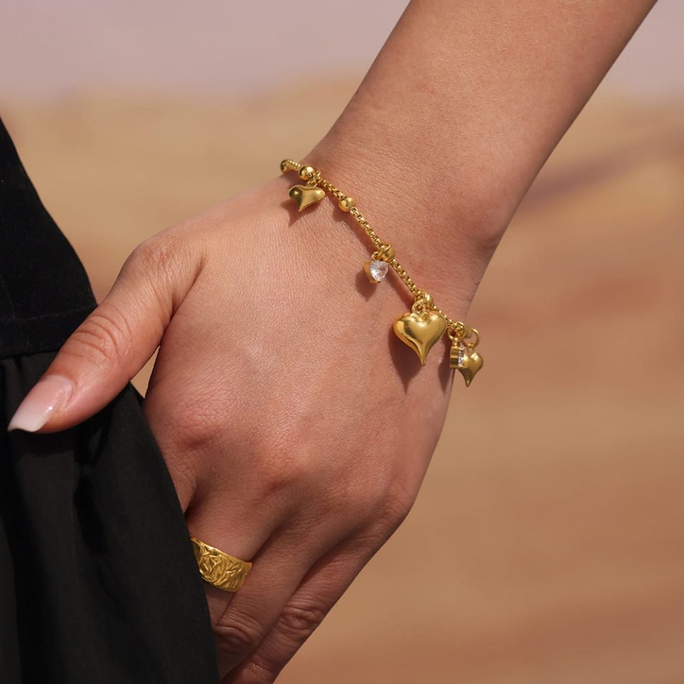 Model with hand in pocket, wearing E596 Gold Heart Pendant Bracelet 17+5cm, showcasing its casual style.