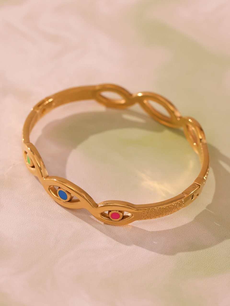Gold evil eye bracelet displayed in an elegant setting with fashion accessories, exuding a sense of luxury and sophistication.