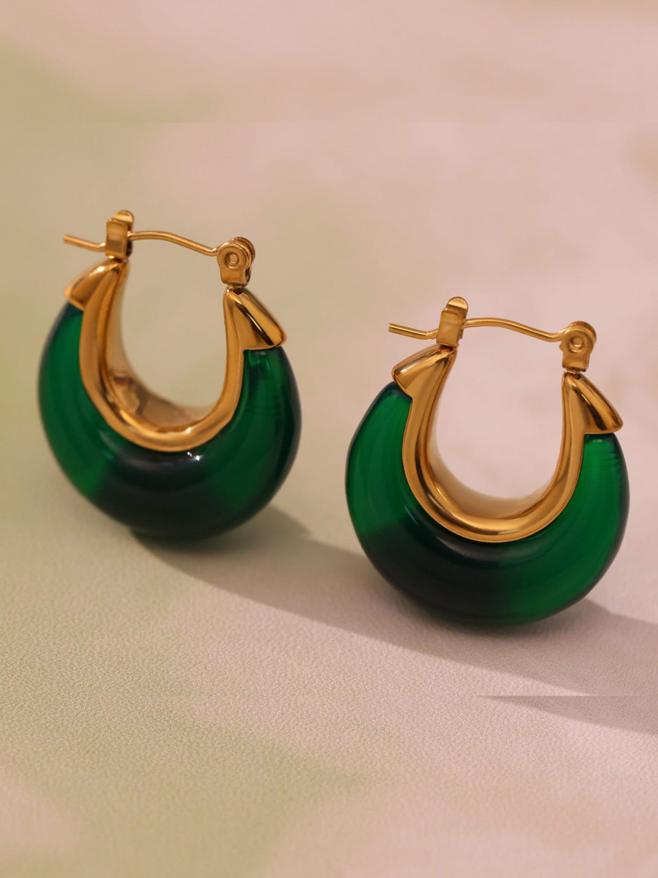 Green resin gold drop earrings displayed in a stylish setting, showcasing their vibrant color and elegant design