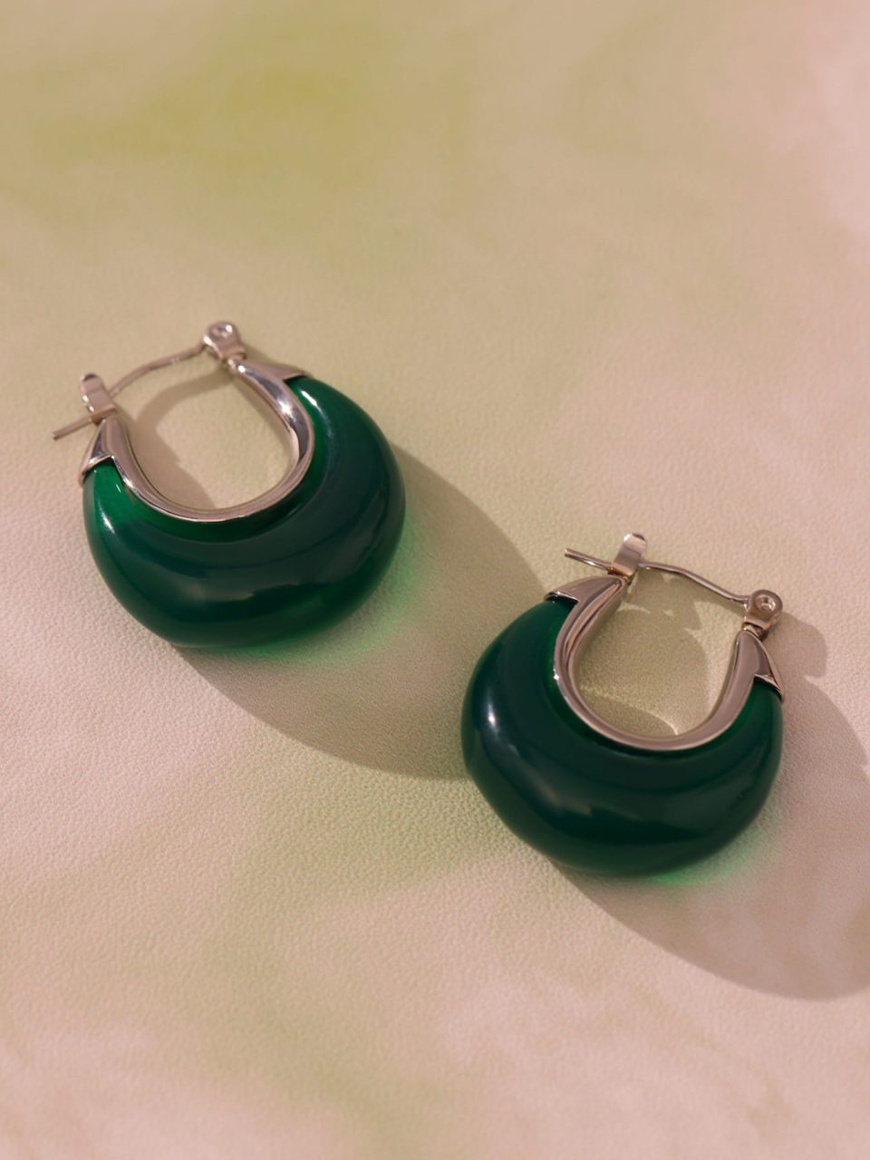 Green resin steel drop earrings displayed in a stylish setting, showcasing their vibrant color and elegant design.