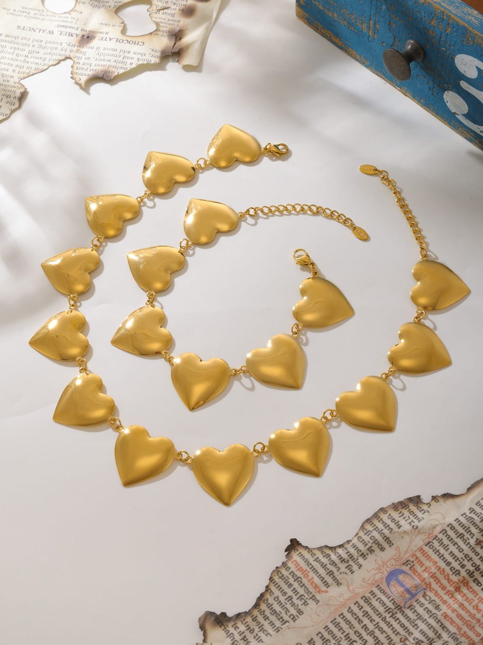 Styled shot of the Bold Heart Chain Choker Necklace & Bracelet Set in mixed silver and gold on marble backdrop
