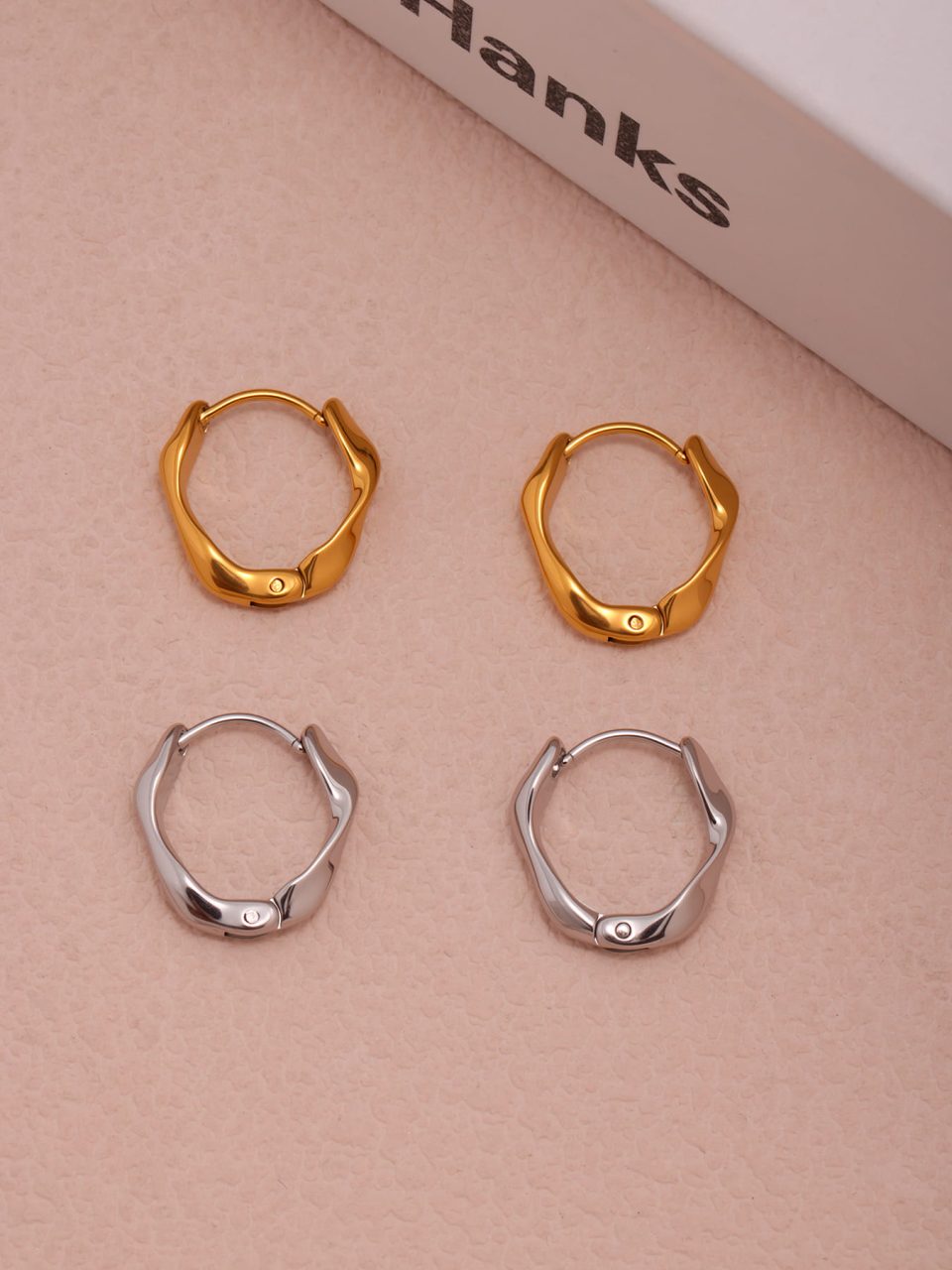 Stylish flat lay of matching gold and silver stainless steel hoop earrings for women on marble surface