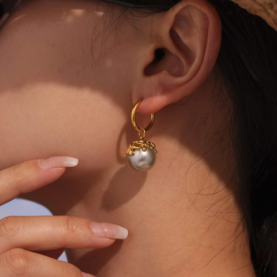 Model wearing Oumaika’s Mini Flower Pearl Drop Earrings in gold finish