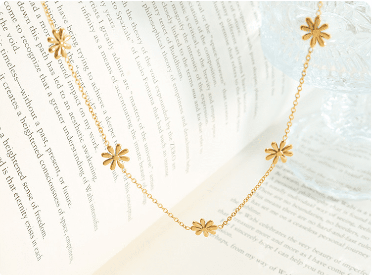 Flatlay of gold daisy flower necklace on vintage newspaper background