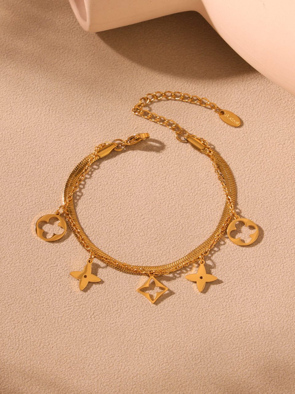 Gold permanent anklet on sandy beach with ocean waves - Oumaika waterproof jewelry lifestyle shot