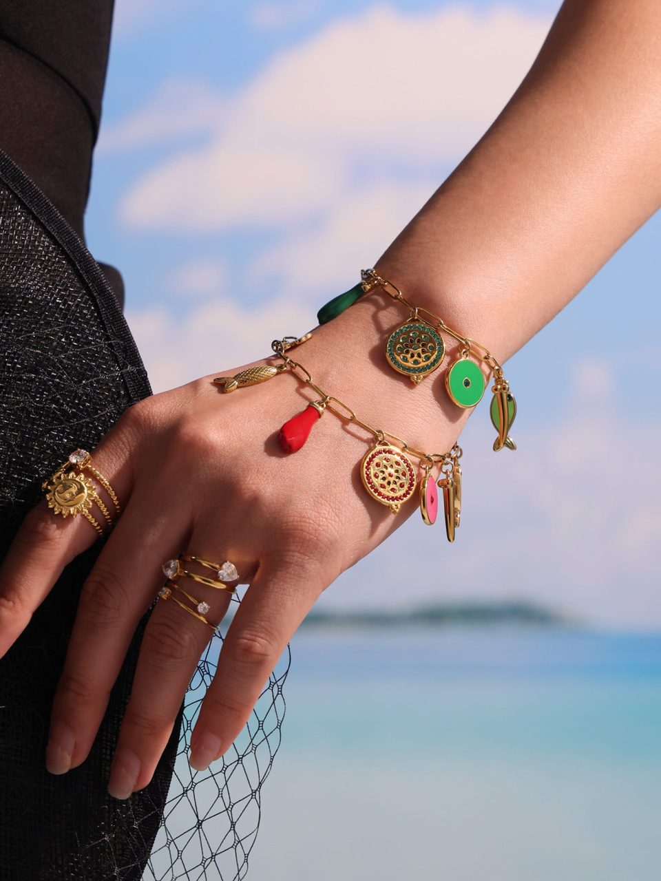 Stylish woman stacking red and green enamel bracelets with V-neck dress for night out