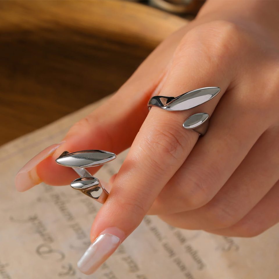 Model hand wearing silver stainless steel open ring with fluid arc design
