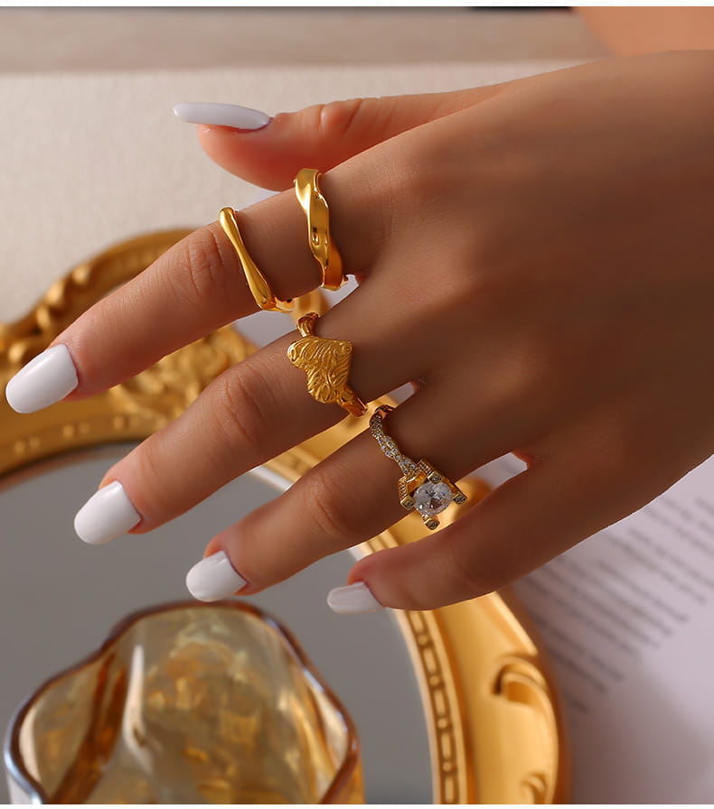 Woman wearing gold textured statement ring with square gemstone, close-up hand shot