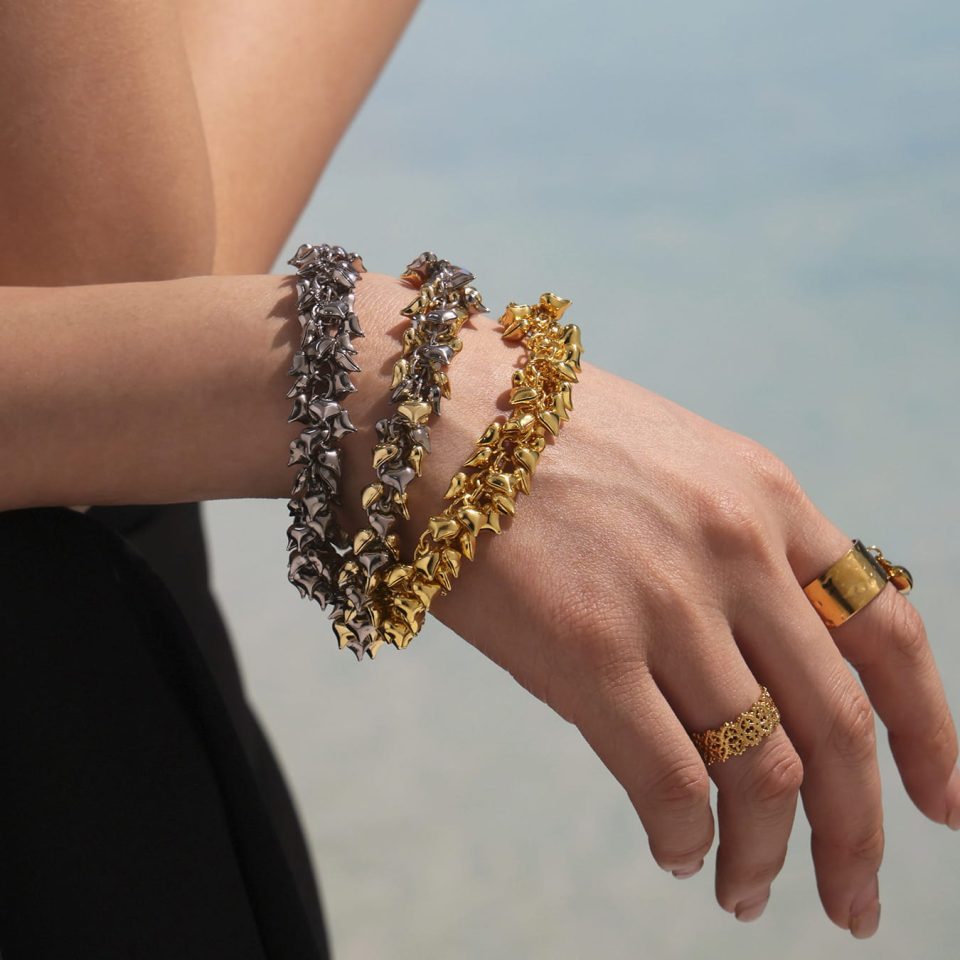 Model wearing chrome hearts inspired ocean wave bracelets in mixed gold, silver and two-tone finishes