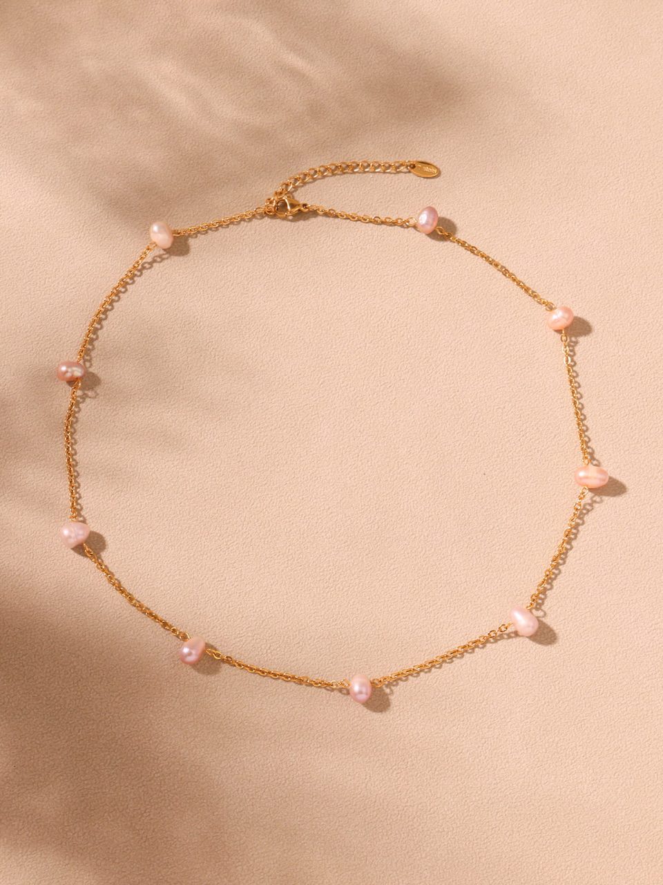 Pink pearl necklace styled with summer outfit on beach - casual jewelry inspiration