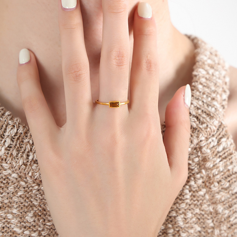 Woman wearing gold stainless steel ring with red cubic zirconia stone on finger