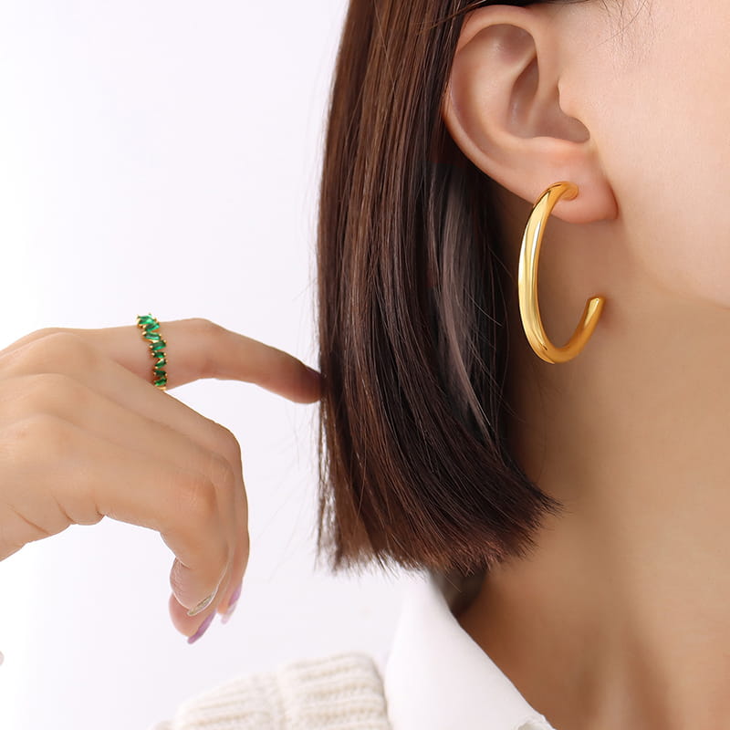 Female model wearing gold stainless steel C-shaped hollow hoop earrings
