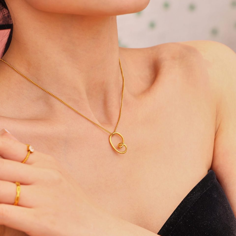 Model wearing the irregular heart pendant necklace layered with other gold chains
