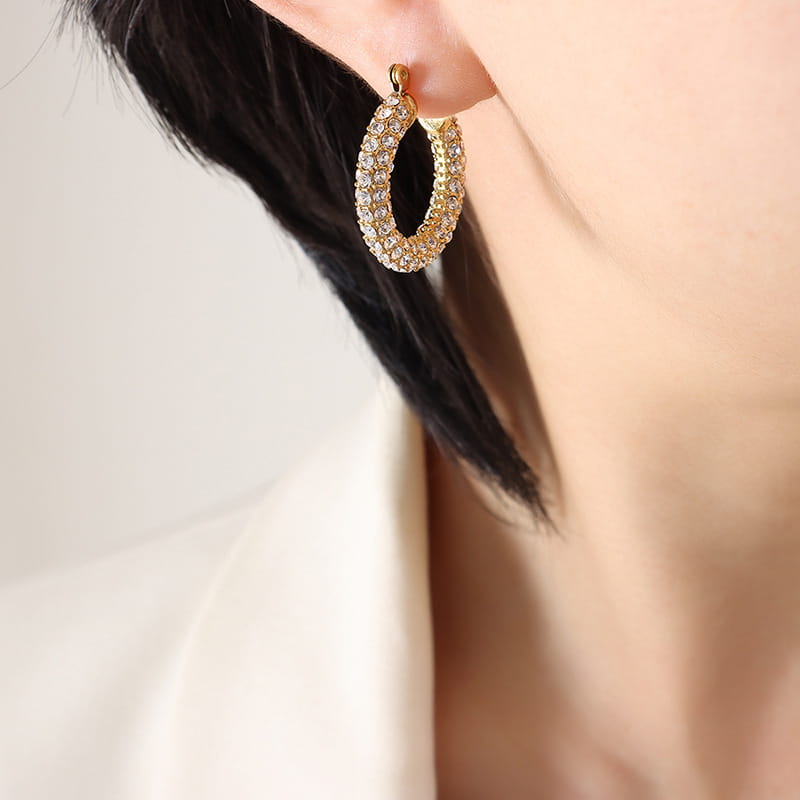Model wearing gold U-shaped hoop earrings with cubic zirconia sparkle