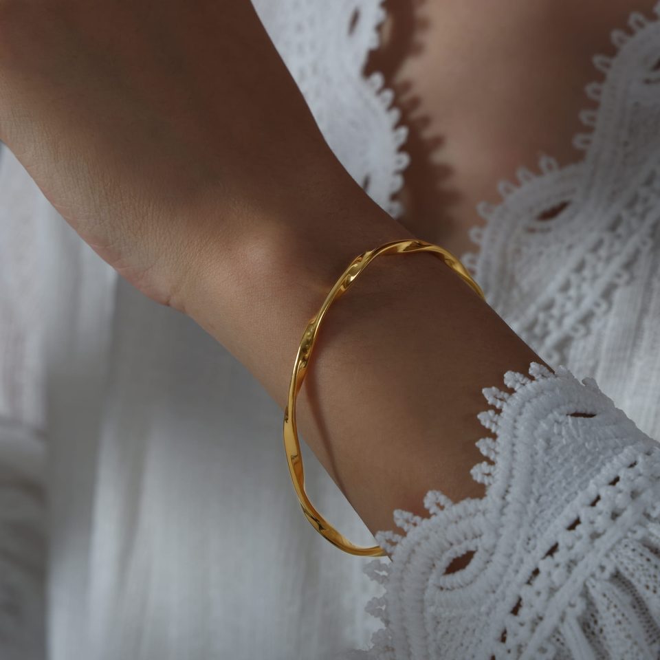Model wearing the minimalist Mobius gold cuff bangle, styled with a clean fashion look