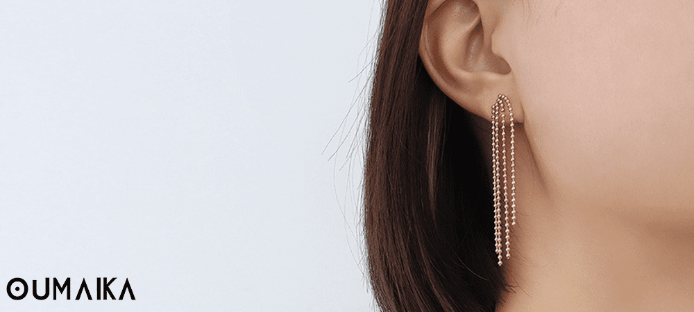 Shell Pearl Tassel Earrings Close-Up Shot Close-up of shell and pearl tassel earrings placed on linen fabric with natural lighting.