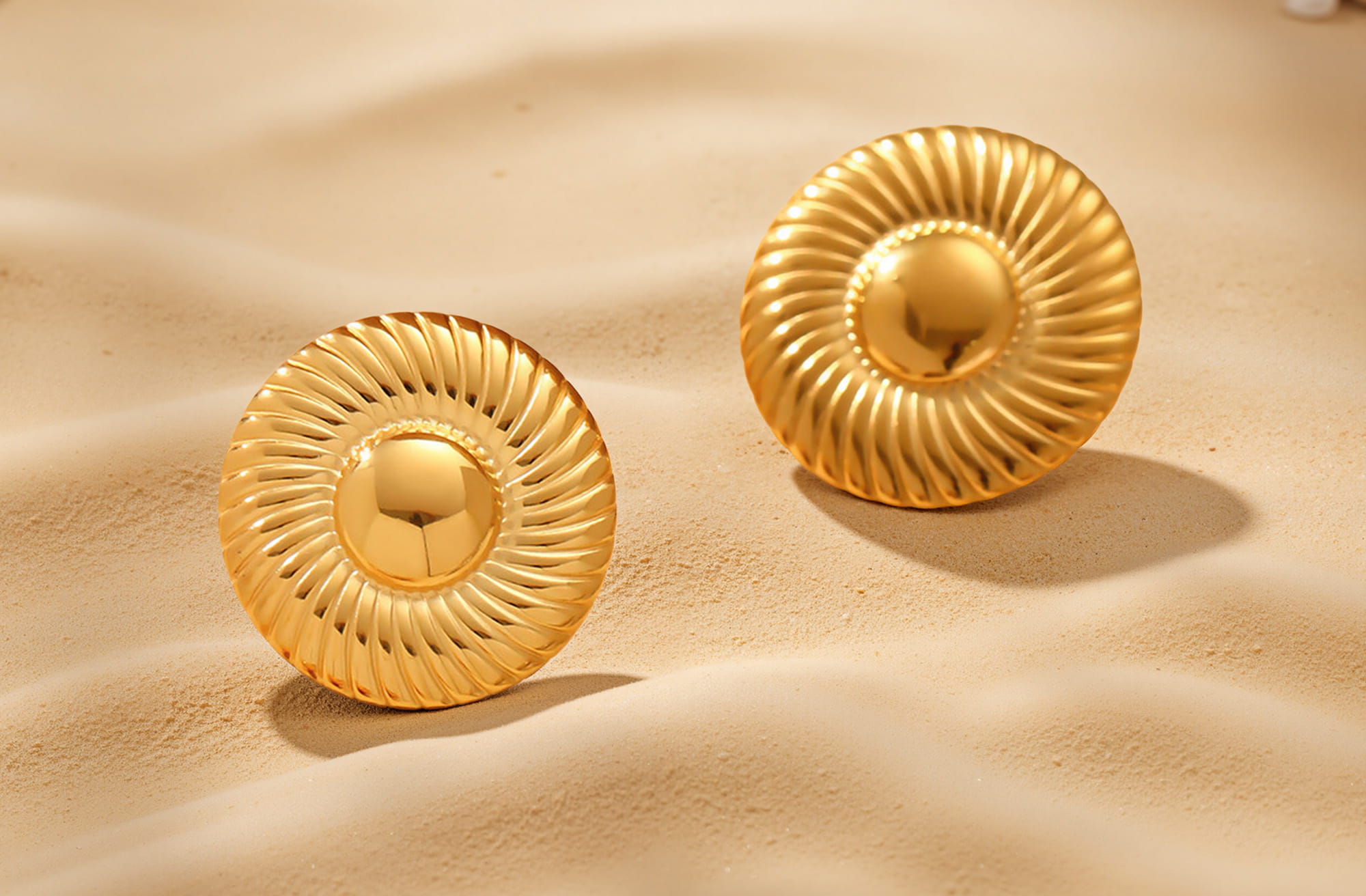Bold round gold statement earrings on soft beach sand