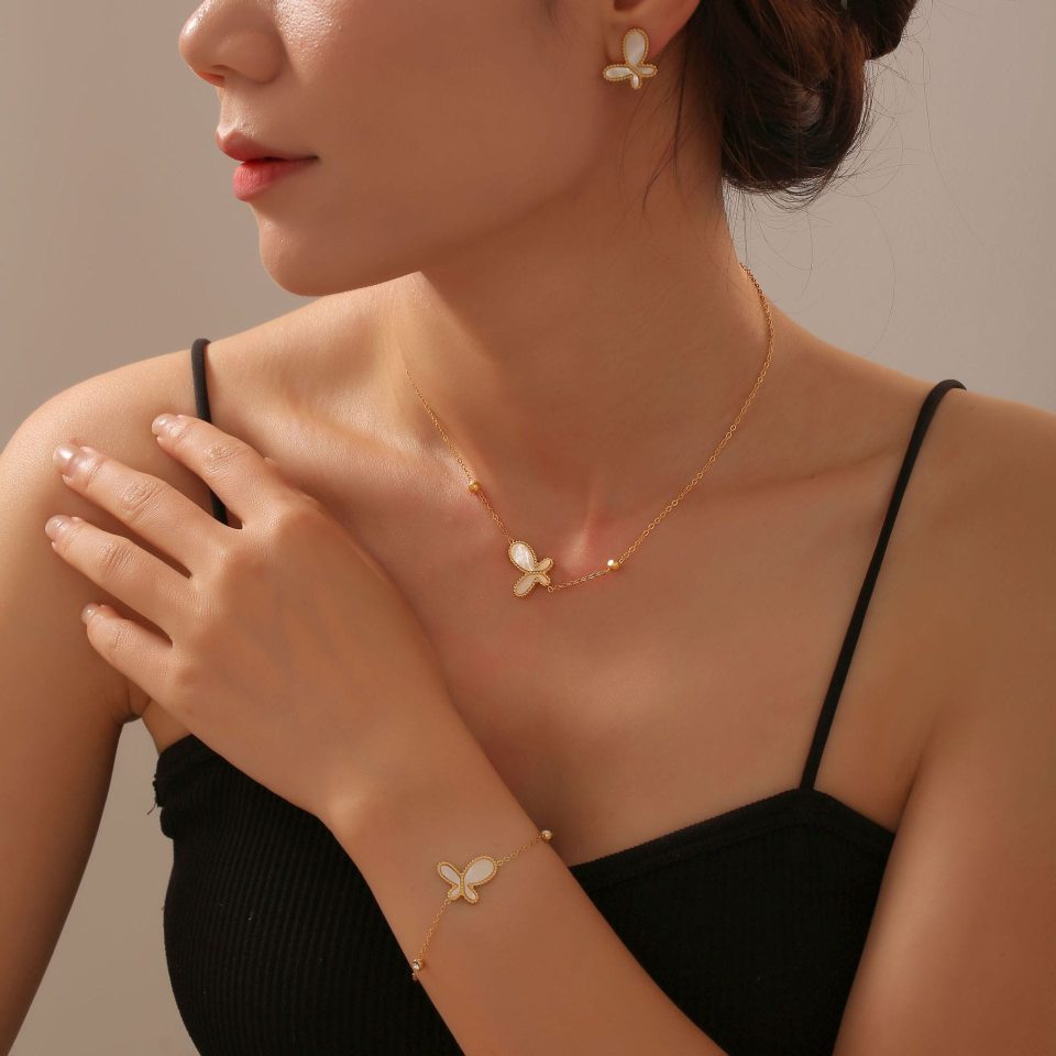 The model is wearing a golden butterfly bracelet