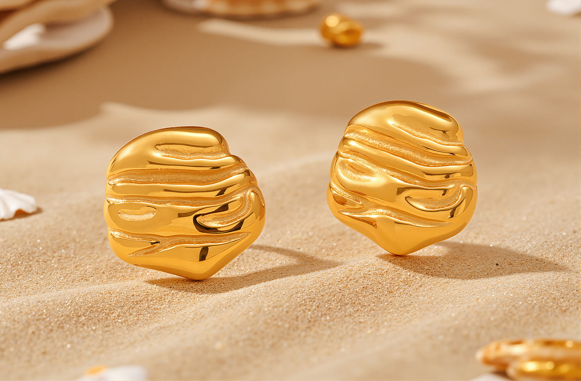 Organic textured gold-tone stud earrings on sand background
