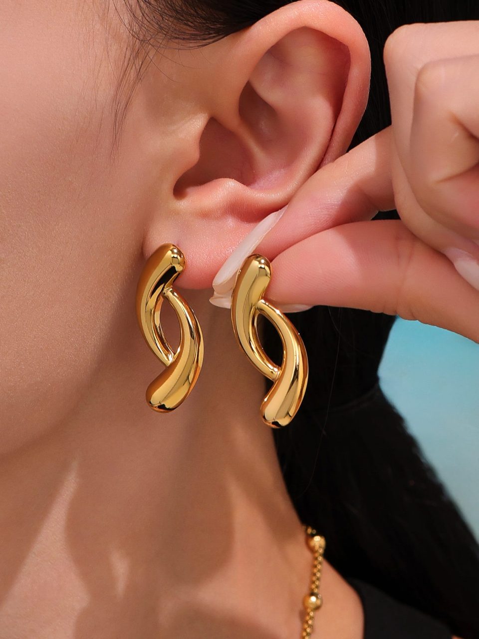 Woman wearing gold teardrop stainless steel colorblock earrings in fashion OL style