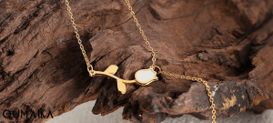 Minimalist teak wood stand holding OumaiKa flower necklace symbolizing sustainable jewelry practices
