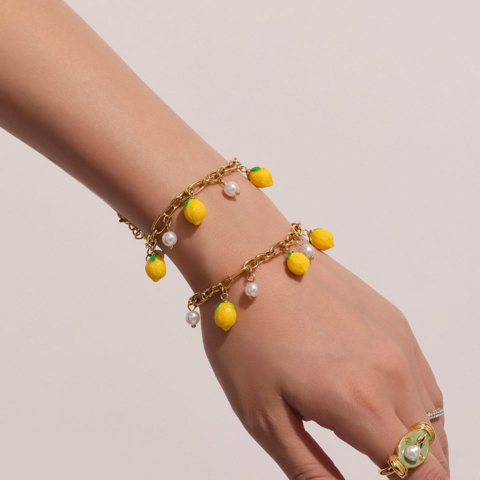 Model wearing gold bead bracelet with lemon resin and shell charms, stainless steel waterproof jewelry