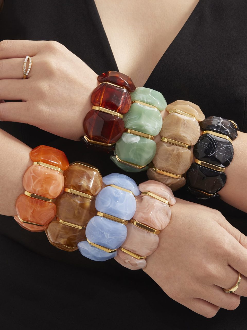 Model wearing stacked black and amber resin bracelets with stainless steel on crossed hands