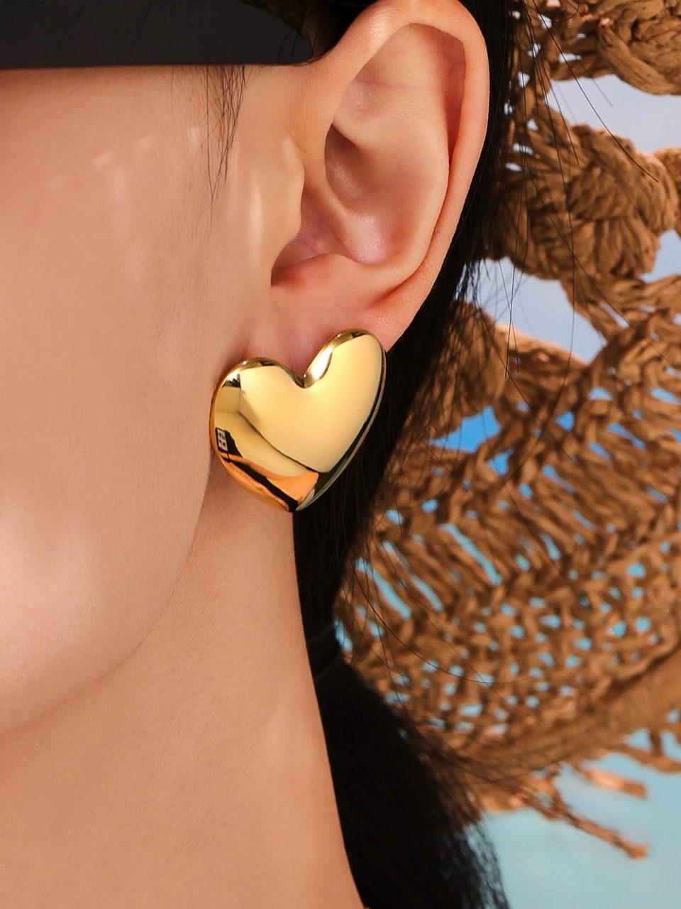 Model wearing Bold Heart Stud Earrings in gold stainless steel