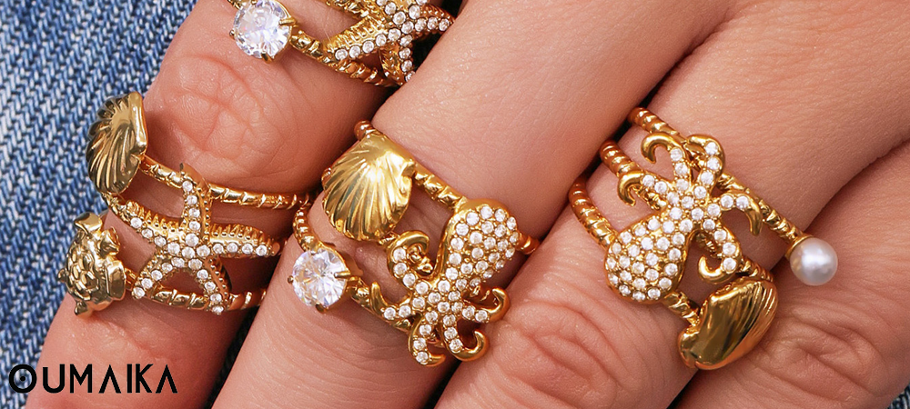 Close-up of gold marine-themed rings with seashell and starfish designs, Oumaika Fall 2025 waterproof jewelry