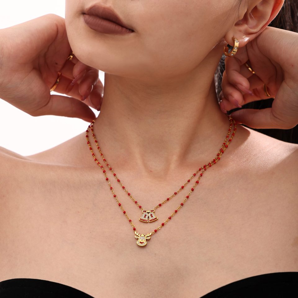 Gold stainless steel Christmas reindeer bell pendant necklace held in hand close-up