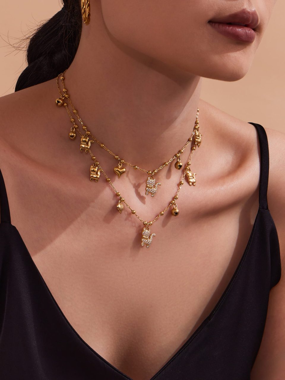 Model wearing Sparkling Cat Bell Pendant Necklace in gold stainless steel with cat charm and zirconia sparkle.