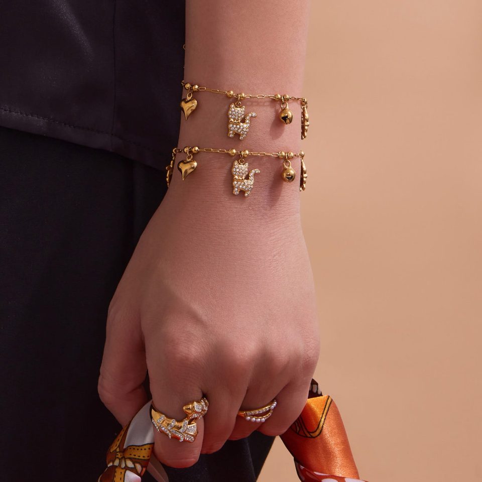 Model wearing gold cat bell charm bracelet with 5A zirconia, stainless steel women’s jewelry